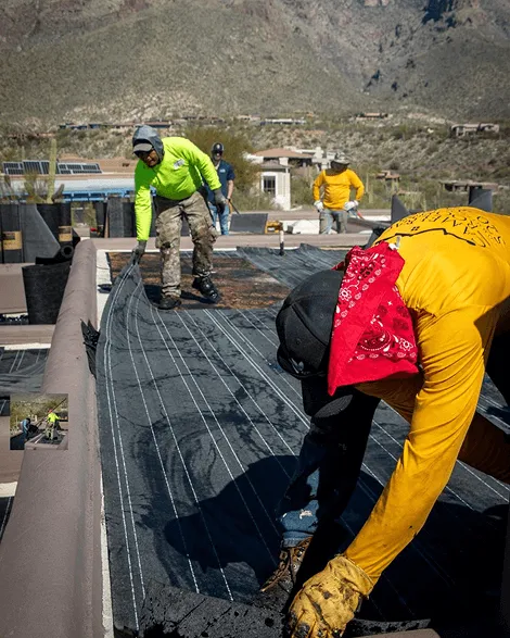 Crew laying down flat roof underlayment, Tucson mountains in the distance